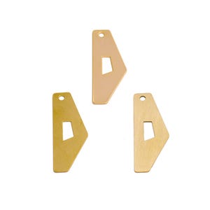 May include: Three geometric metal pendants in gold and brass tones. Each pendant has a unique shape with a rectangular cutout and a small hole at the top for stringing. The pendants are displayed against a white background.