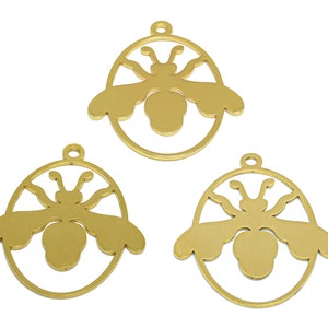 May include: Three gold-coloured metal bee charms with a cutout design. Each charm is shaped like an oval with a bee silhouette inside.