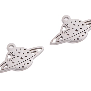 May include: Two silver metal charms shaped like a planet with a ring around it. The planet has a sun and stars design.
