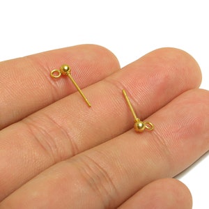 以下が含まれることがあります： 小さなループが上部にあり、ボールが下部にある、2つの金色のイヤリングポスト