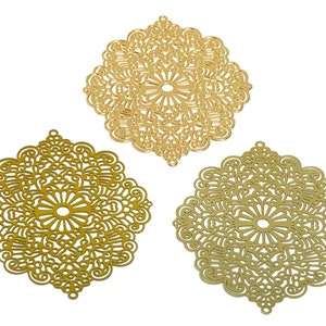 Könnte beinhalten: Drei goldene filigranartige Verzierungen aus Metall mit komplizierten Designs. Jede Verzierung ist ein Quadrat mit abgerundeten Ecken und einem floralen Muster.