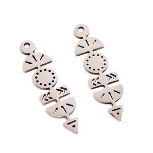 Könnte beinhalten: Ein Paar silberfarbene Ohrringe mit einem abstrakten Design. Jeder Ohrring hat eine Reihe geometrischer Formen, darunter Halbkreise, Kreise mit kleinen Löchern und Dreiecke. Die Ohrringe haben oben einen Stecker zum Tragen.