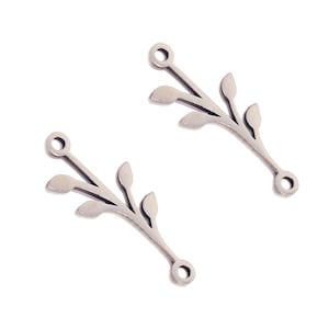May include: Two silver-colored metal leaf branch charms. Each charm has a small loop at the top and bottom for attaching to jewelry. The charms have a delicate, minimalist design with three leaves.