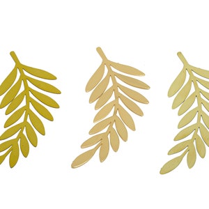 May include: Three gold-colored metal leaf shapes, each with a different shade of gold. The leaves are cut out of metal and have a delicate, intricate design.