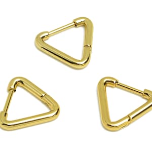 May include: Three gold triangle-shaped hoop earrings. The earrings are made of a thick, smooth metal.