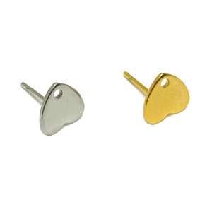 May include: Two heart-shaped earring studs, one silver and one gold. Each stud has a small hole at the top.