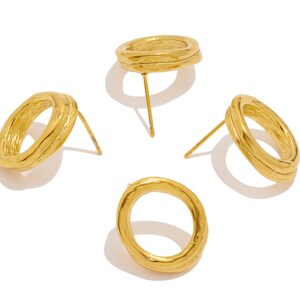 May include: Four gold-toned hoop earrings with a textured surface. The earrings are arranged in a circle on a white background.