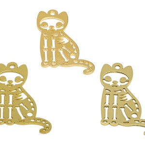 Puede incluir: Tres abalorios de metal de color dorado con forma de gato con un diseño de esqueleto. Los abalorios tienen un bucle en la parte superior para sujetarlos a un collar o pulsera.