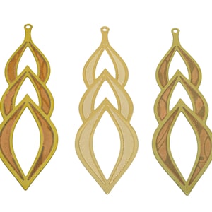 May include: Three gold-colored metal pendants with a layered, teardrop design. Each pendant has a different pattern, one with a woodgrain texture, one with a hatched pattern, and one with a smooth surface.