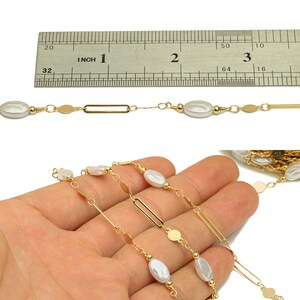 以下が含まれることがあります： 真珠が白く、楕円形をした、金色のチェーンネックレス。チェーンは丸いリンクと長方形のリンクが混ざっています。ネックレスは定規で測定されており、長さは2.5cmです。