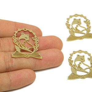 Pode incluir: Tr&ecirc;s pingentes de metal dourado com uma raposa sentada em um livro aberto com uma coroa de louro ao redor.