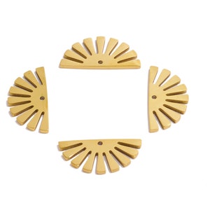 Puede incluir: Cuatro formas de sol de metal dorado, cada una con un agujero en el centro. Las formas están dispuestas en forma de cuadrado.