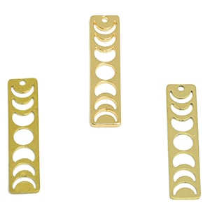 May include: Three gold metal charms shaped like a rectangle with a crescent moon design cut out. The charms are approximately 2 inches long and 1/2 inch wide.