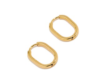 May include: Two gold-colored oval hoop earrings. The earrings have a smooth, polished finish and a simple, elegant design. The hoops are a medium size, suitable for everyday wear. The earrings are displayed on a white background.