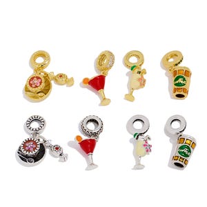 May include: A selection of charm pendants in gold and silver. The charms depict a teacup, cocktail, a person with a drink, and a coffee cup. The charms are detailed with colourful enamel.