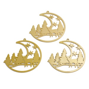May include: Three gold metal crescent moon ornaments with a deer and pine trees cut out. Each ornament has a small hole at the top for hanging.