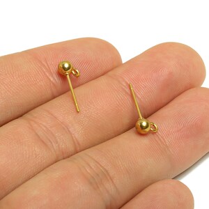 以下が含まれることがあります： 小さなボールが上部にあり、ループが下部にある、2つの金色のイヤリングポスト