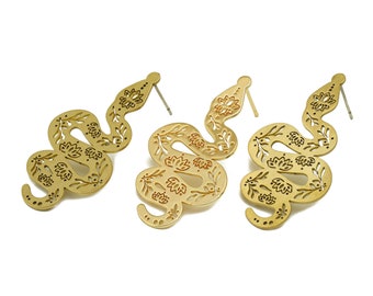 May include: A pair of gold-tone snake earrings with a floral design. The earrings are made of metal and have a post back.