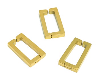 May include: Three gold-colored metal clasps, each with a rectangular shape and a hinged opening. The clasps are designed to be used for attaching or connecting items.