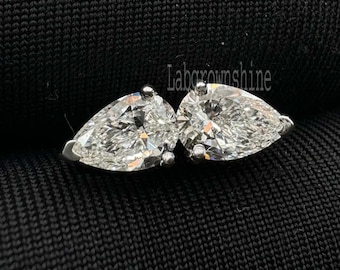 Puede incluir: Un par de pendientes de diamantes con forma de pera. Los diamantes están engastados en una montura de plata u oro blanco. Los pendientes se muestran sobre un fondo negro.