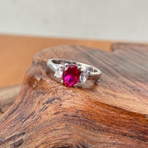 Może przedstawiać: Biały ceramiczny kubek z czarnym uchwytem i napisem "But First, Coffee" czarną, odręczną czcionką. Kubek stoi na białej powierzchni.