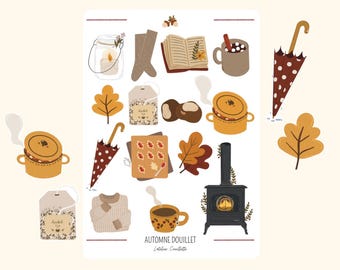 Op de afbeelding: Een illustratie met herfstthema's, waaronder een kaars, laarzen, een boek, warme chocolademelk, een paraplu met stippen en een kleine kachel. De tekst "AUTOMNE DOUILLET" is ook aanwezig.