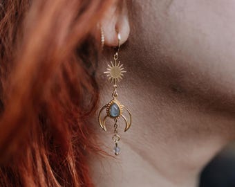 Könnte beinhalten: Goldfarbene Hängeohrringe mit Sonne, Mond und tropfenförmigem Edelstein. Die Ohrringe hängen an einem kleinen Reifen und werden am Ohr getragen. Das Design ist aufwendig und detailliert, mit einer Boho-Ästhetik.