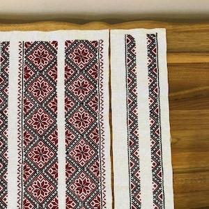 Peut inclure: Pièces de tissu blanc avec broderie au point de croix détaillée. Le motif présente des motifs géométriques en rouge, noir et blanc, notamment des motifs de diamants et de fleurs. Ces pièces font probablement partie d'un projet textile plus vaste.