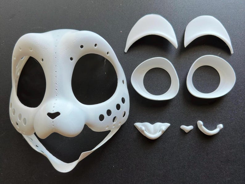 May include: A white plastic mask with holes and a nose, along with separate pieces for eyes, eyebrows, and a mouth.