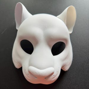 May include: White blank animal mask with large ears and black eye holes. The mask is made of a smooth, textured material.