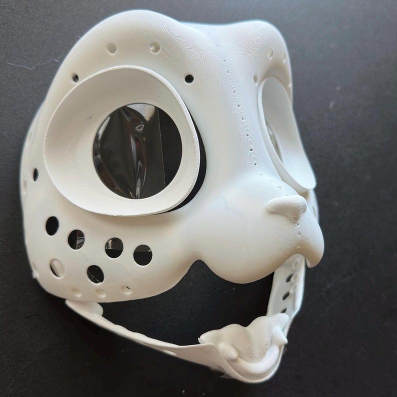 May include: White 3D printed animal mask with a large eye hole and a small nose. The mask has a textured surface and is designed for use as a costume or prop.