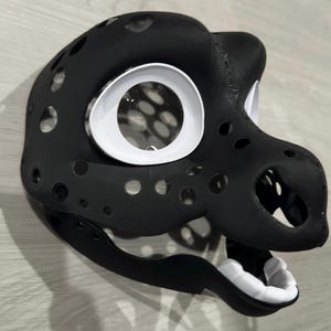 May include: Black and white furry mask with a detailed design. The mask has a large, white eye and a small, white mouth.