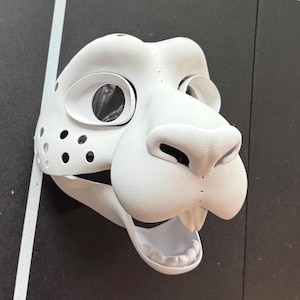 May include: White unfinished furry animal mask with open mouth and visible teeth. The mask has two eye holes and a nose.