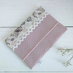 Op de afbeelding: Een roze stoffen etui met een witte kanten rand en een bloemenpatroon. Het etui heeft een wit stippenpatroon en een wit label met het woord "Willow" erop.