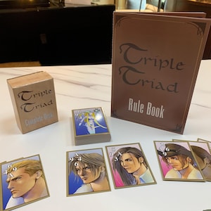 May include: A complete deck of Triple Triad cards in a brown box with the text "Triple Triad Complete Deck". A brown rule book with the text "Triple Triad Rule Book" is next to the box. There are several cards with illustrations of characters from the game.