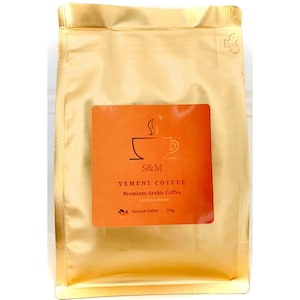 Könnte beinhalten: Ein goldener Beutel mit jemenitischem Kaffee mit einem Etikett mit der Aufschrift "S&M Yemeni Coffee Premium Arabic Coffee Medium Roast Ground Coffee 250g"