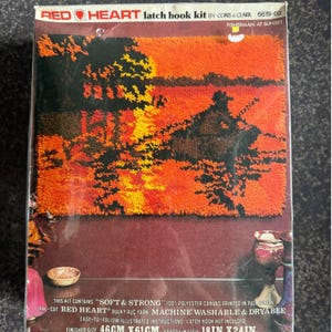 May include: A Red Heart latch hook kit titled Fisherman at Sunset, model 6619-02. The box displays a finished rug with a black, orange, and yellow sunset scene. Text indicates a finished size of 46cm x 61cm or 18in x 24in.