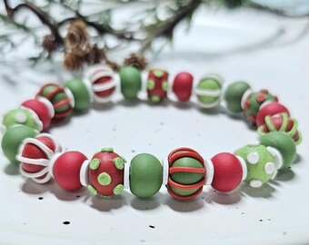 May include: A beaded bracelet featuring a repeating pattern of round and textured beads in shades of red, forest green, and lime green, accented with small white spacer beads and beads wrapped in thin red or white decorative wire.