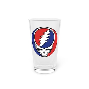 May include: A clear glass pint glass with a red, white, and blue Grateful Dead Steal Your Face logo printed on the front.