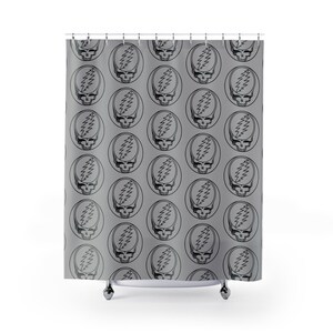 May include: A gray shower curtain featuring a repeating pattern of black skull and lightning bolt designs within a circular frame. The design is a stylized representation of a skull with a lightning bolt on the forehead.