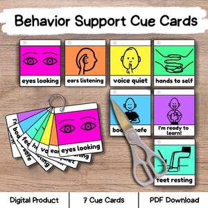 May include: A set of colorful cue cards for behavior support, featuring illustrations and text such as "eyes looking" and "ears listening." The cards are arranged on a wooden surface, with a pair of scissors and a ring of cards visible.