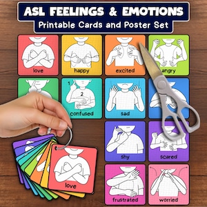May include: A set of ASL Feelings & Emotions printable cards and a poster featuring colorful squares with illustrations of hand signs for various emotions. The cards are held together by a metal ring, and a pair of scissors is placed on the poster.