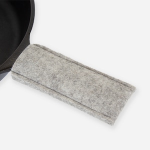 May include: A gray felt handle cover for a cast iron skillet. The cover is designed to protect hands from heat.