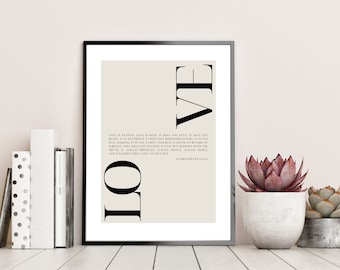 May include: A beige printable wall art print with a black frame. The print features the word "LOVE" in large black letters with a vertical line separating the letters. The print also includes a quote about love from the Bible, 1 Corinthians 13:4-8.