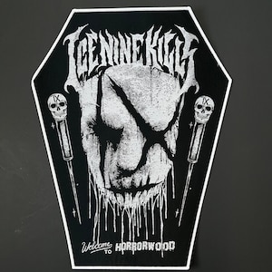 May include: A black and white coffin-shaped patch with the band name Ice Nine Kills. The design features a face with an X over the eyes, dripping details, and the text "Welcome to Horrorwood". Two skull-topped daggers are on either side of the face.