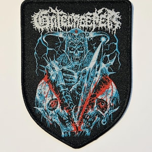 May include: Black patch with a shield shape featuring a blue and red illustration of a skeletal warrior holding a sword. The patch has the band name "Gorgoroth" in white, stylized lettering across the top.