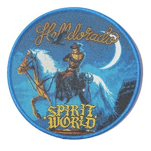Puede incluir: Parche redondo bordado en azul con un vaquero montado a caballo blanco bajo una luna creciente. El parche presenta el texto "Hell Dorado" y "Spirit World" en letras doradas. Un pájaro vuela sobre el vaquero.