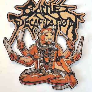 May include: An embroidered patch featuring a multi-armed, seated figure with a bull's head. The figure is adorned with skulls and knives. The text "Cattle Decapitation" is written in a stylized font above the figure.