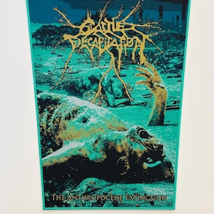 May include: A rectangular wall tapestry featuring a teal and black graphic print of a post-apocalyptic landscape with a decaying figure. The gold text reads Cattle Decapitation at the top and The Anthropocene Extinction at the bottom edge.