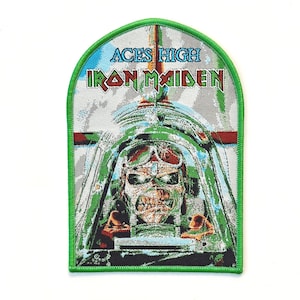 May include: A rectangular embroidered patch with a rounded top edge and a bright green border. The design features a pilot in a cockpit with the text ACES HIGH and IRON MAIDEN in red and green lettering against a grey and blue sky background.